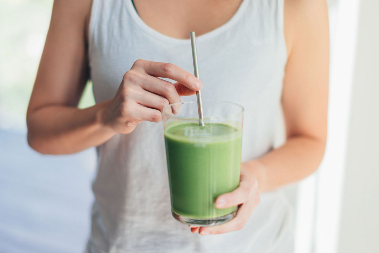 young woman drinking vegan smoothie with metal straw
