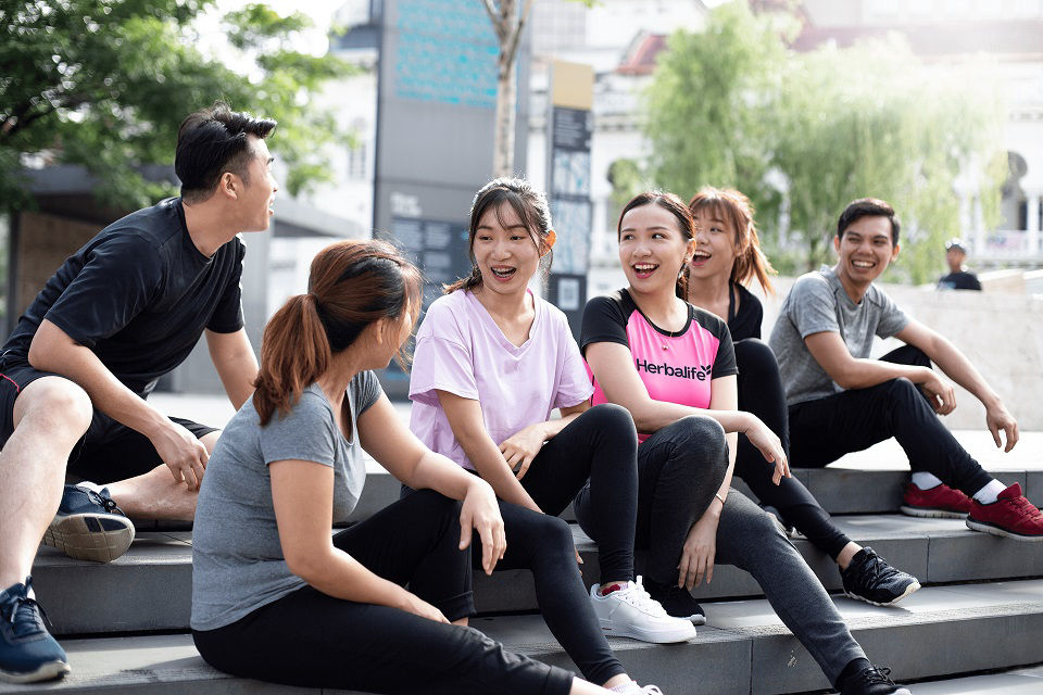 Friends resting on steps after a jog, Group of young people relaxing and chatting after their workout in a city setting