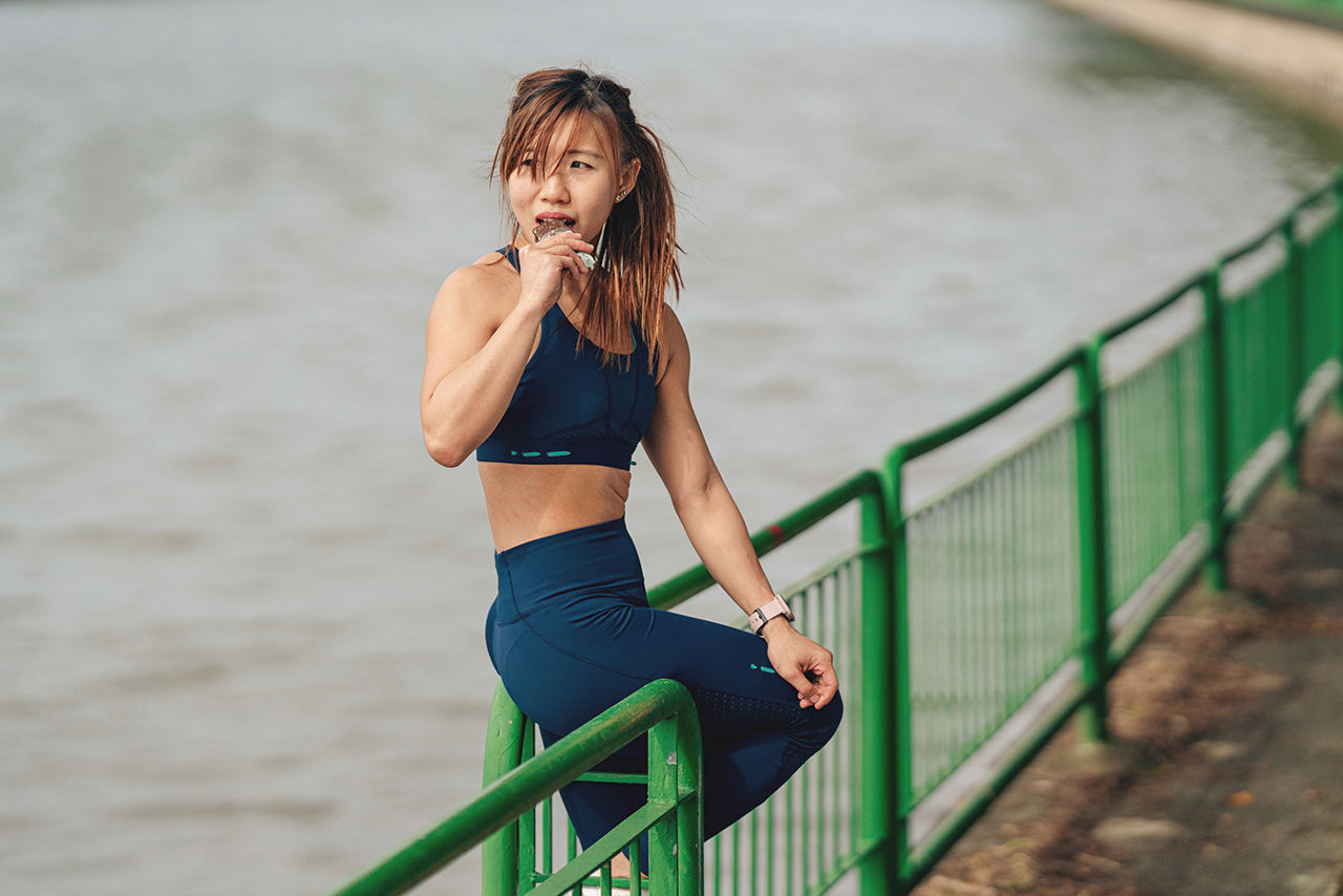 Asian woman eating an energy bar between exercise