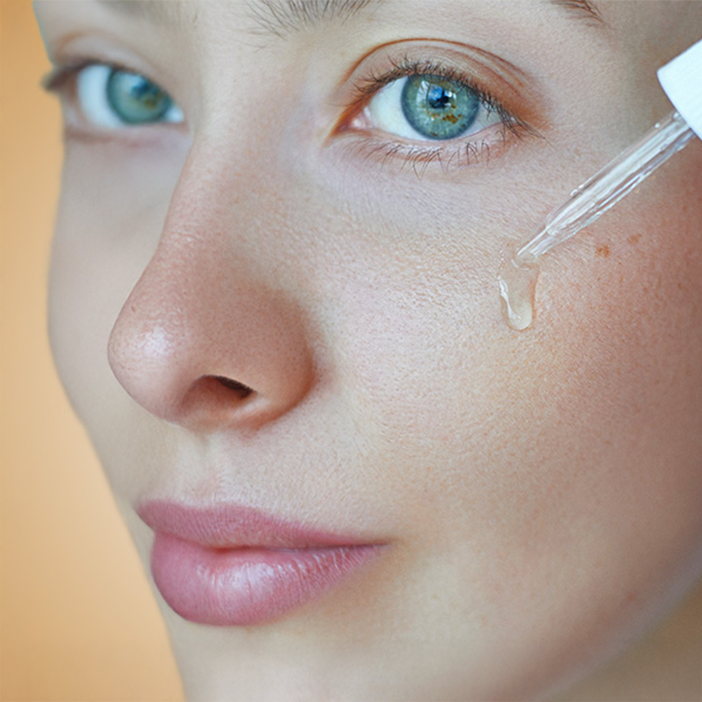 Μια γυναίκα εφαρμόζει τον ορό HL/Skin Niacinamide στο πρόσωπό της.