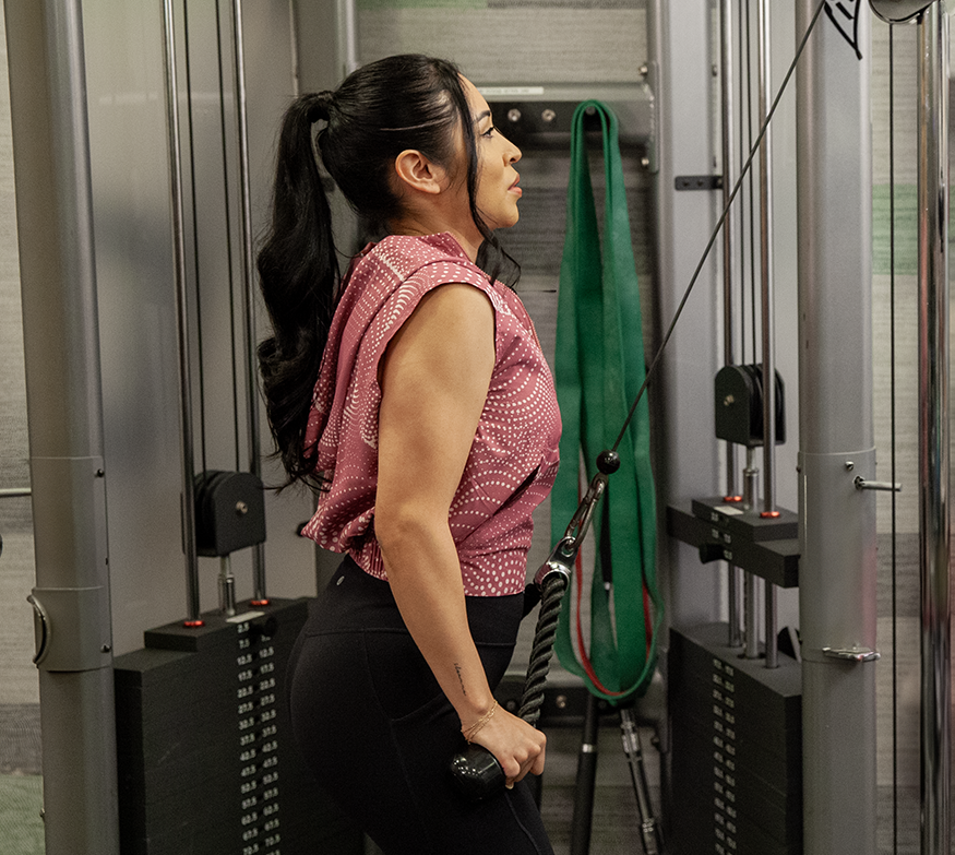A woman performs cable pulldowns at the gym.