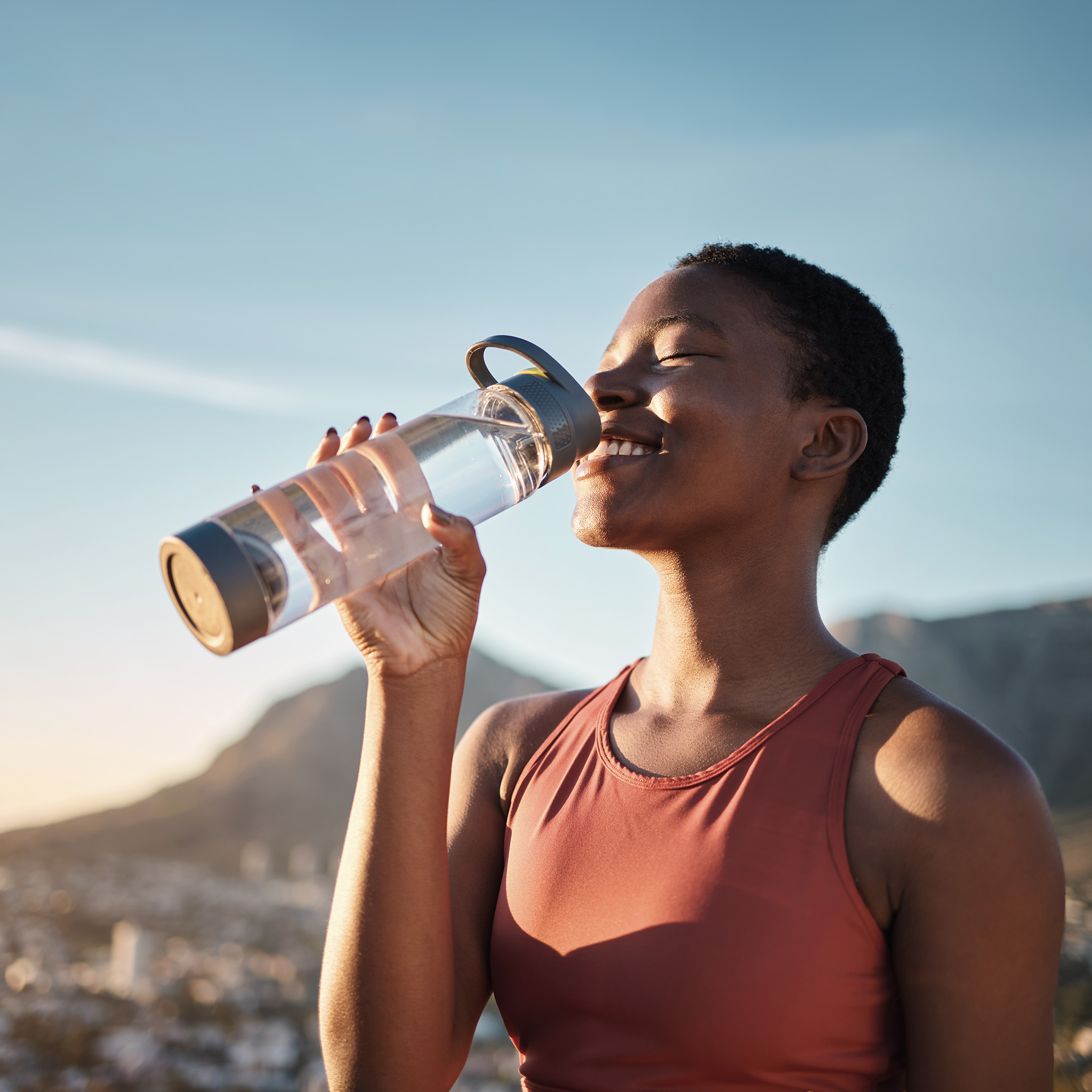 Person drinking water outdoors after exercise