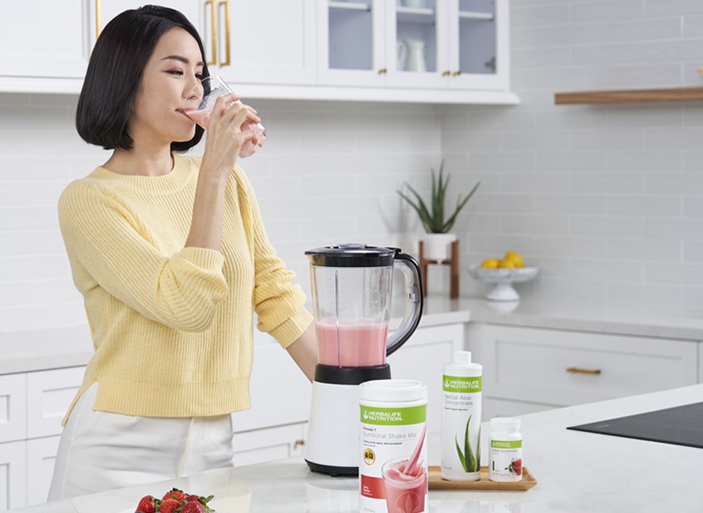 Asian woman drinking a protein shake in her kitchen