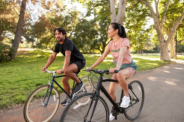 Hombre y mujer montando sus bicicletas en un parque.