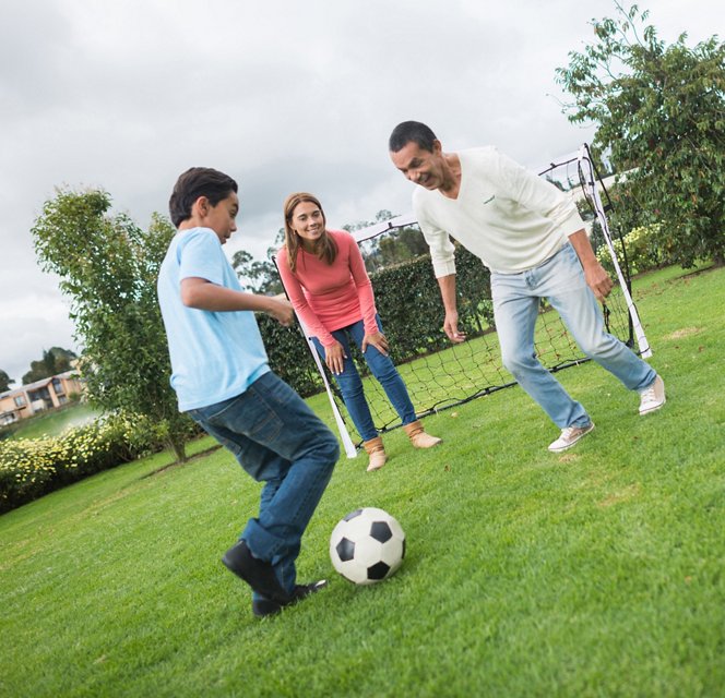 Mother, father, and son enjoy playing soccer outdoors