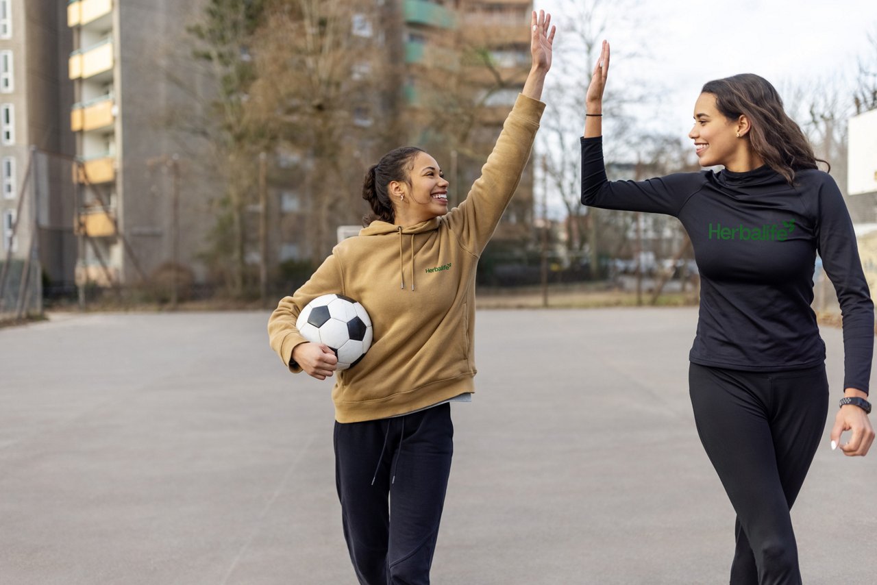 Two female soccer players celebrate by high-fiving after a match