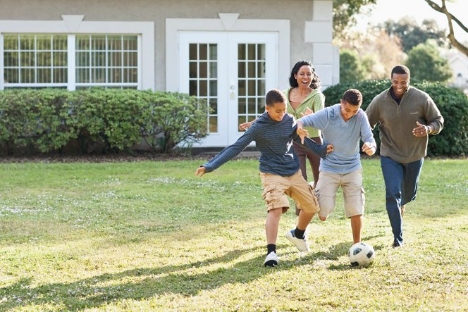 Family playing soccer in their backyard