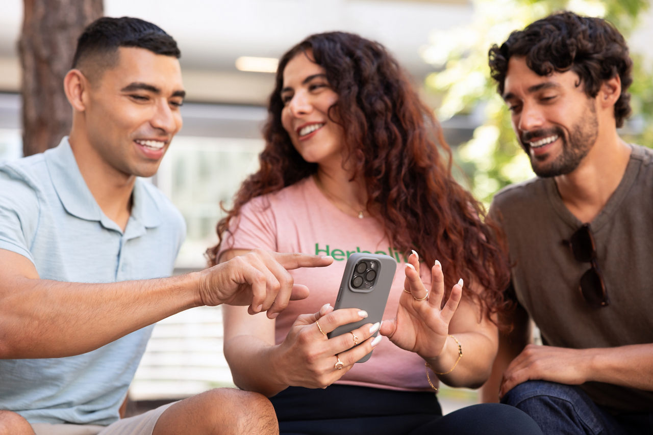 hree friends discussing Herbalife Business Opportunities after looking at cellphone