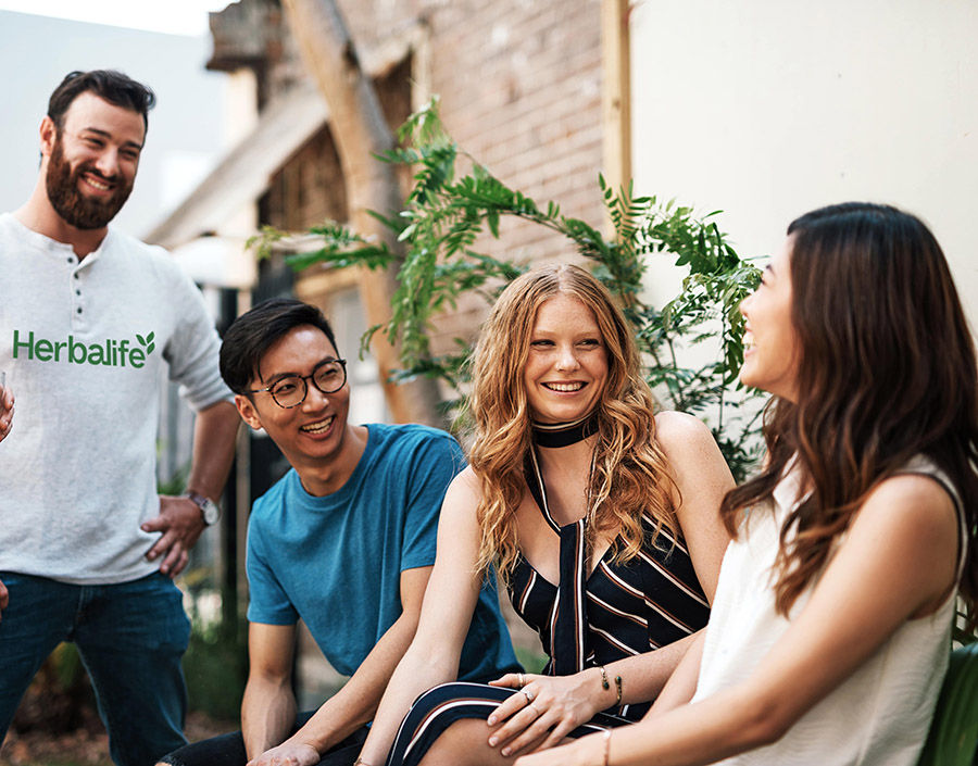 Herbalife community outdoors, Group of young people, friends and family gather on social event or barbecue in the garden on sunny summer day. Multi ethnic group of people enjoy spending day together