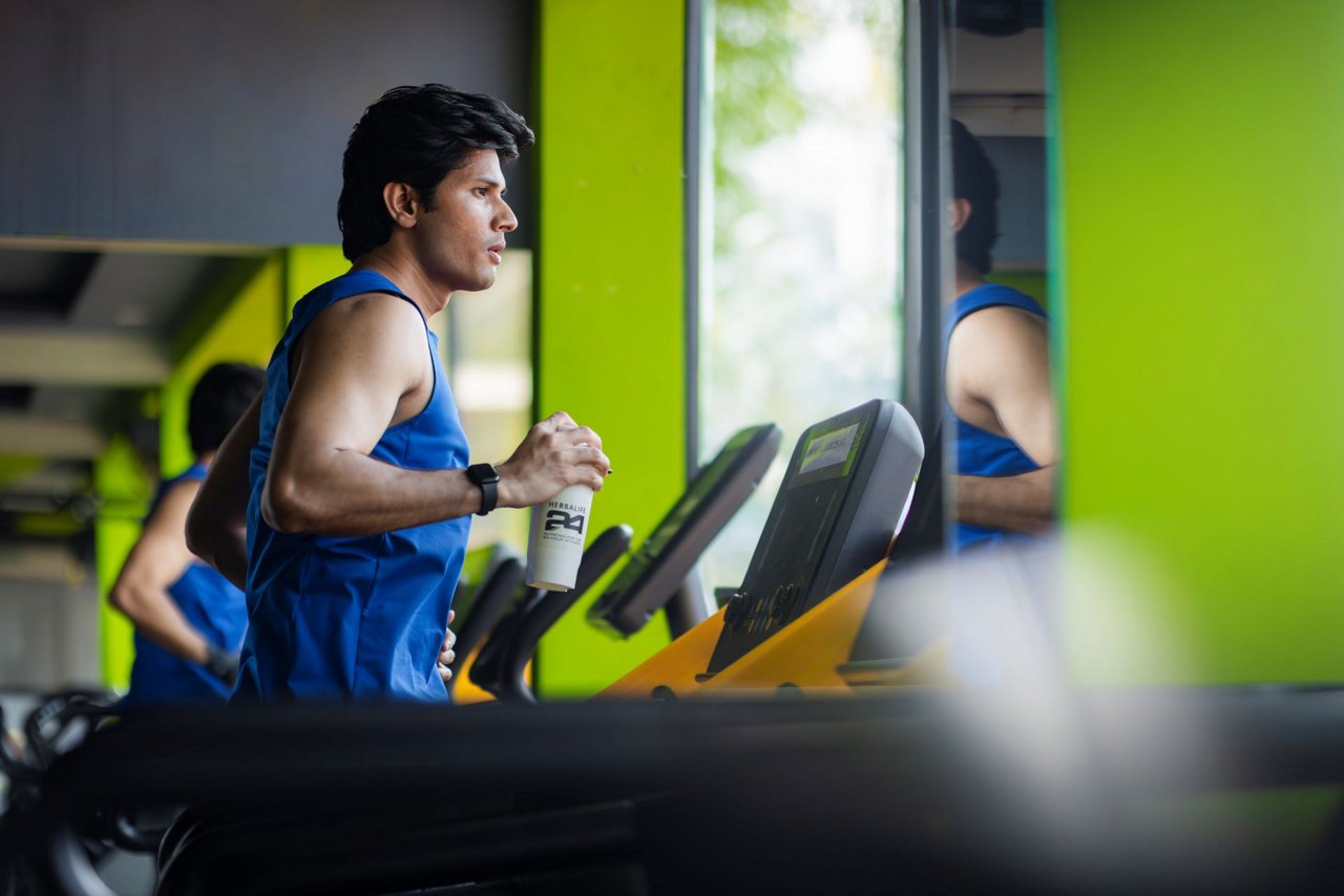 हाथ पर हर्बालाइफ शेकर के साथ जॉगिंग करता एक आदमी