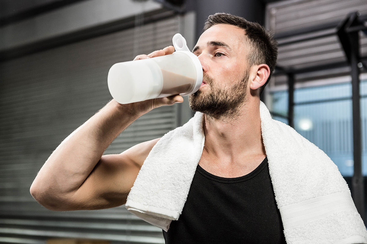 Man in gym drinking shake.