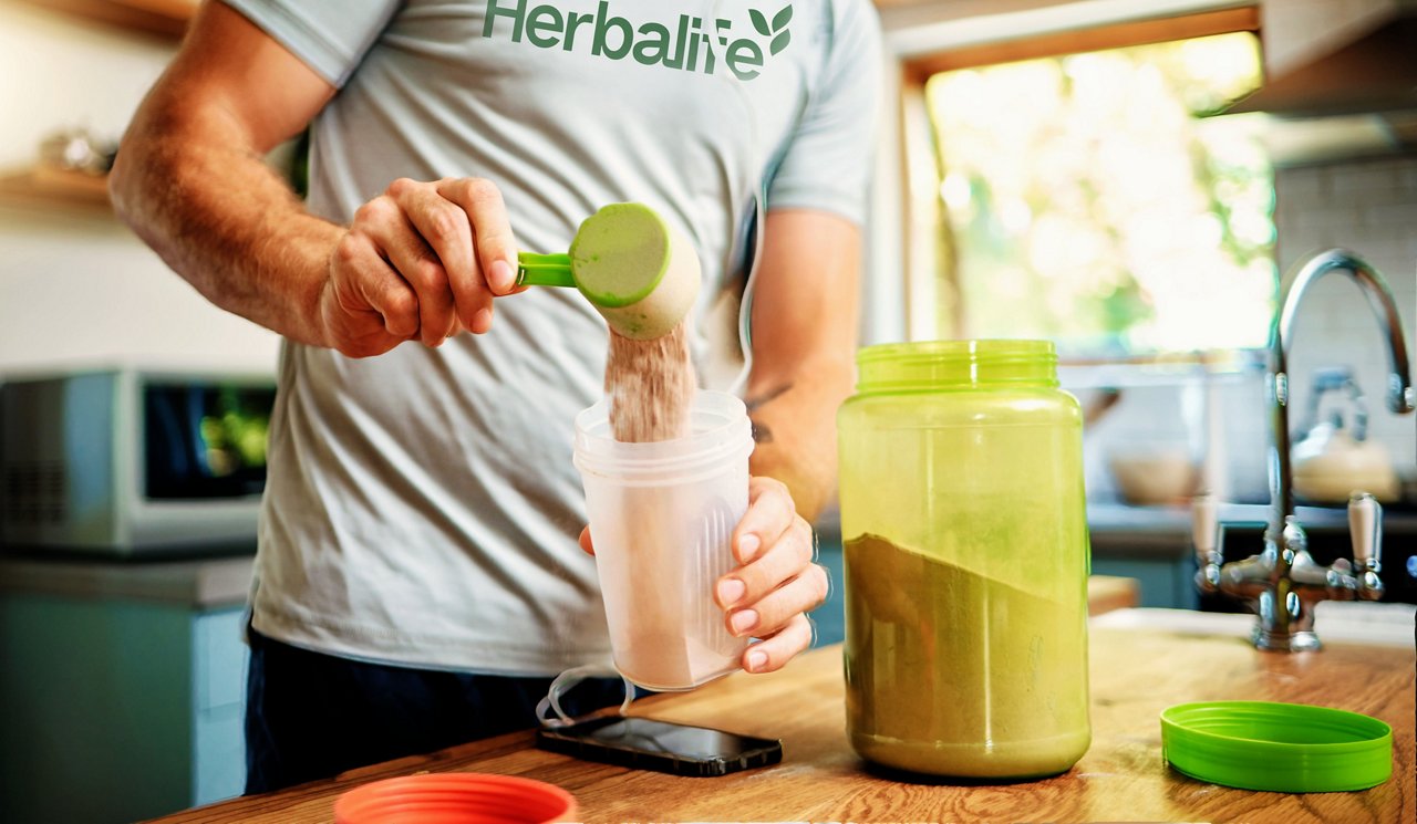 Man serving protein powder in a shaker in a kitchen