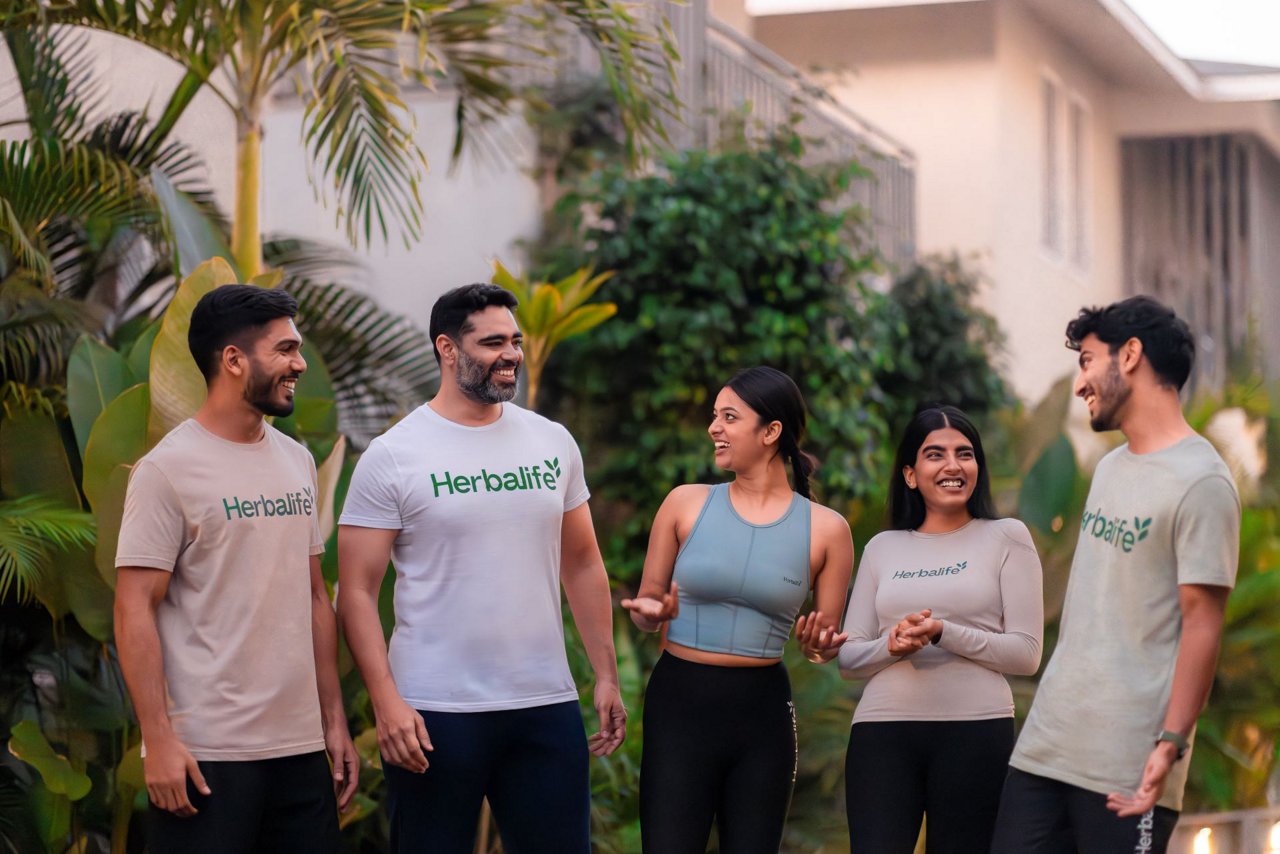Herbalife टी-शर्ट पहने हुए पुरुष और महिला हंसते हुए