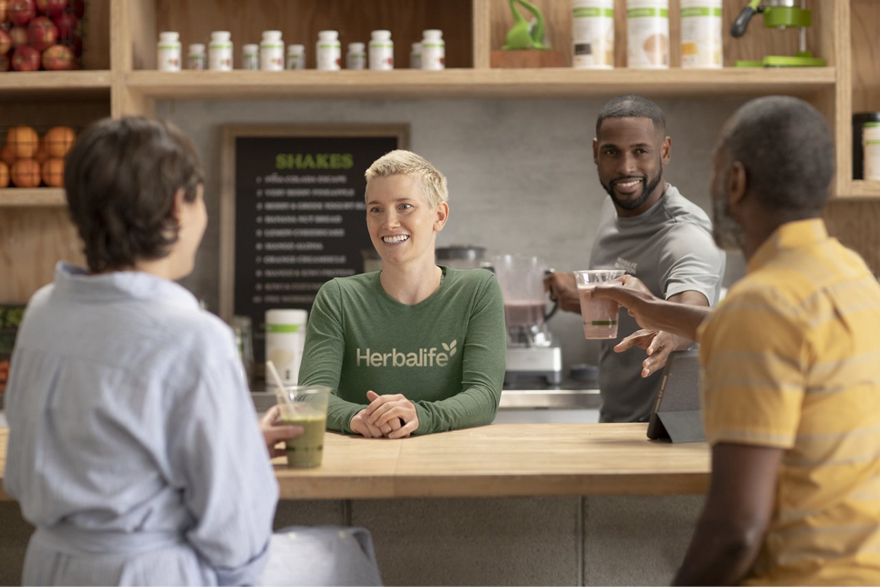 Herbalife distributors and customers at a Nutrition Club chatting and enjoying shakes