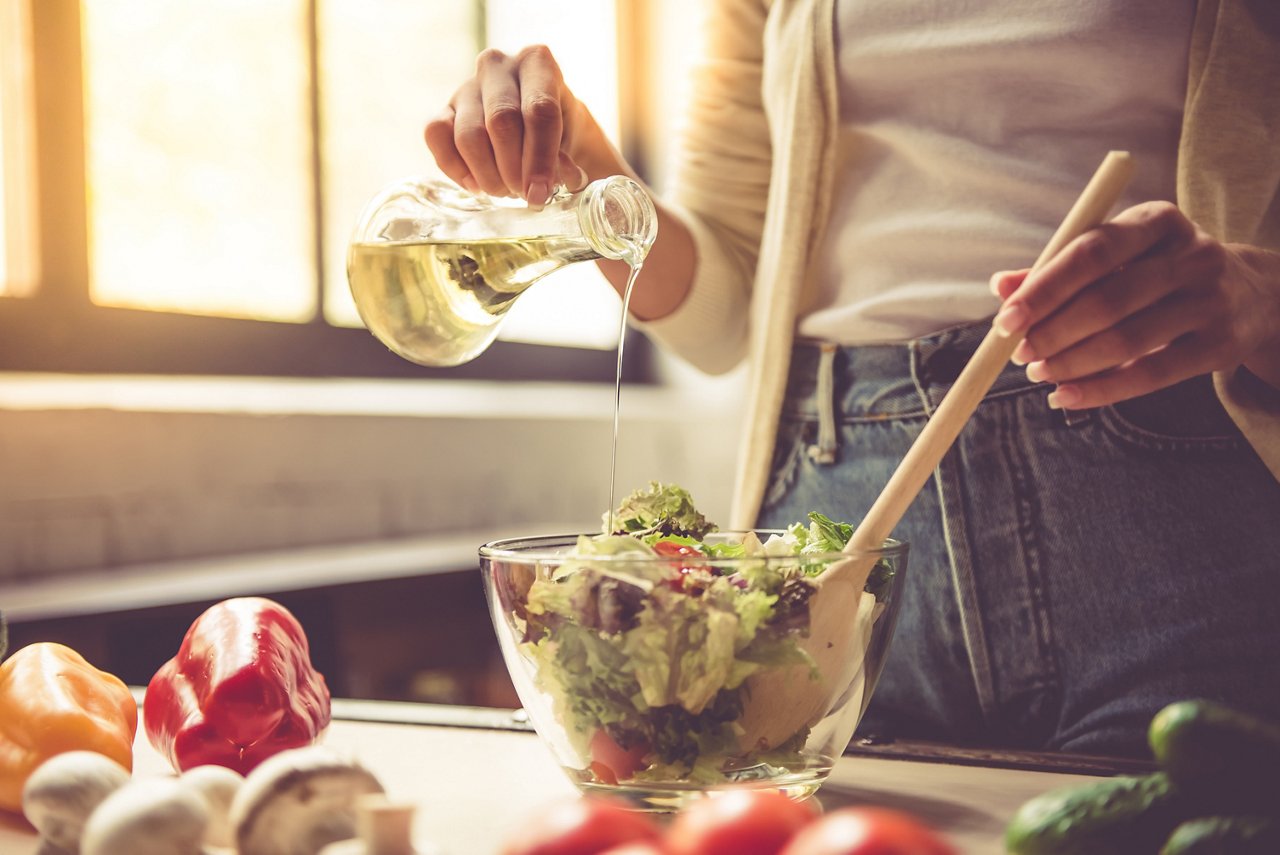 woman pouring oil over salad