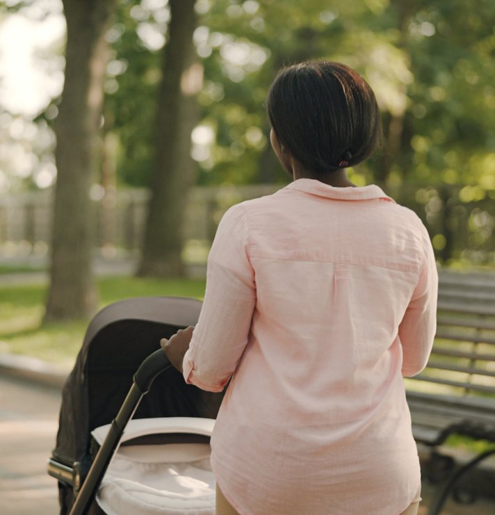 Woman pushing a pram on a walk in the park