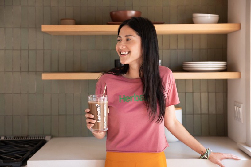 Woman smiling and drinking a shake in the kitchen