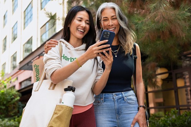 Dos mujeres riendo y mirando un teléfono.