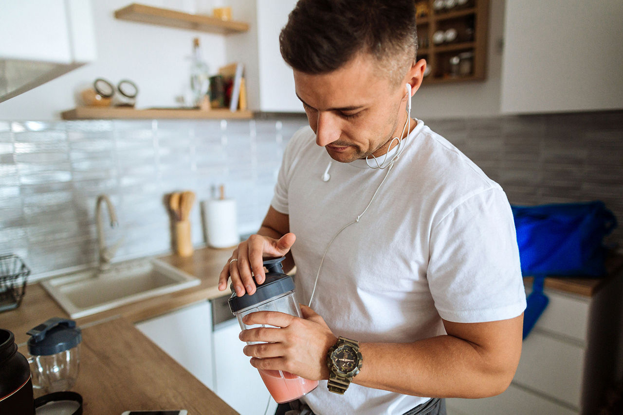 Man makes a protein shake in kitchen