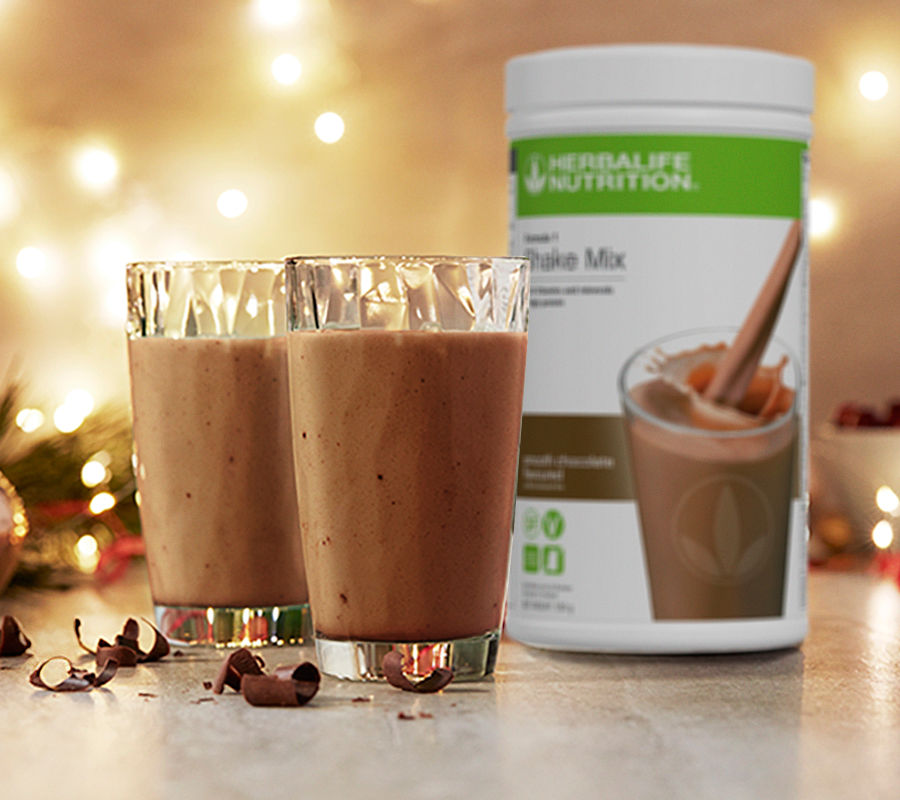 Herbalife chocolate protein shake for the holidays, placed on a table with a warm festive background. 