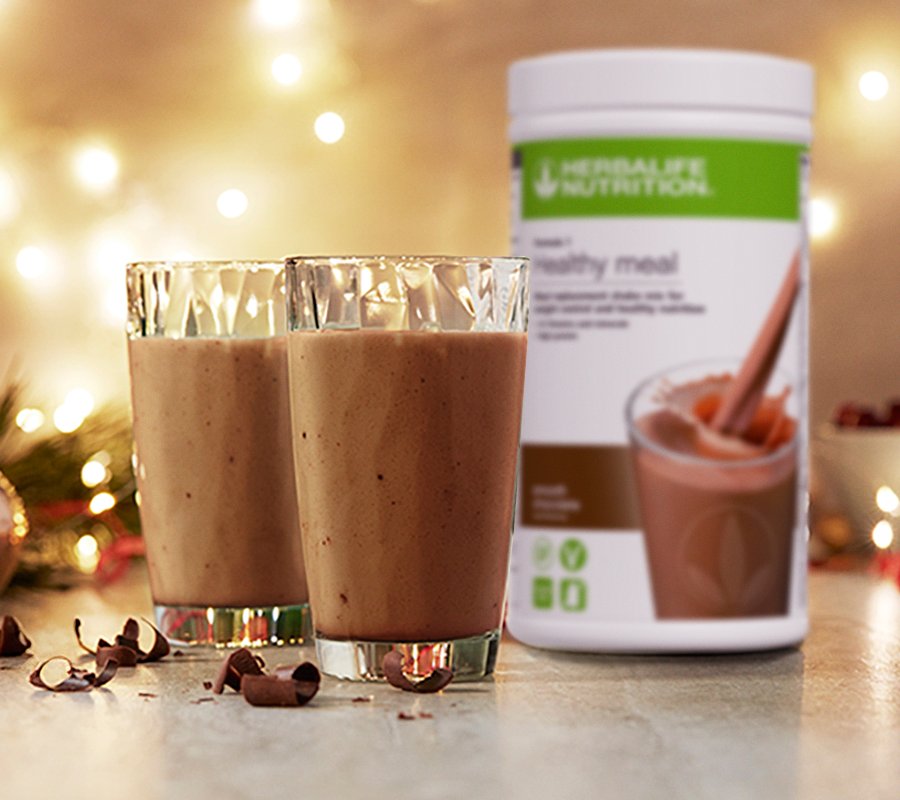 फेस्टिव डेकोर के बीच मेज़ पर रखा Herbalife का स्वादिष्ट चॉकलेट प्रोटीन शेक।