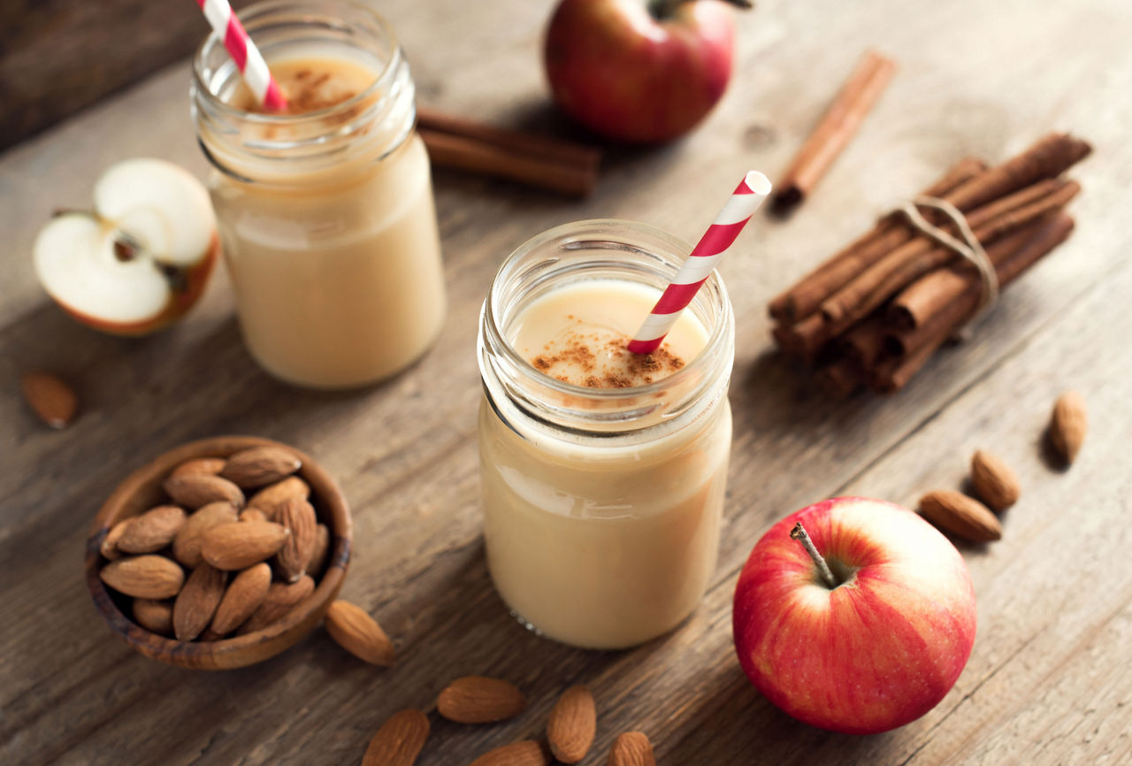 Apple pie protein smoothie drink with almond milk. Homemade apple smoothie with apple pie spices (cinnamon) on wooden background, copy space.