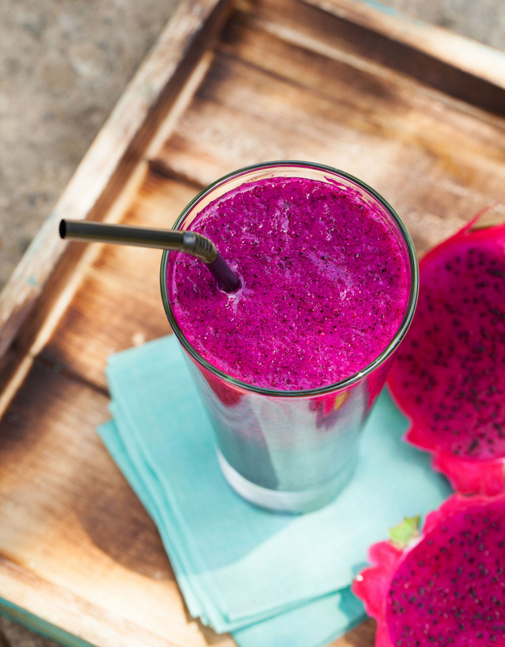 Glass of dragon fruit smoothie, juice and fresh pitahaya on a outdoor tropical background