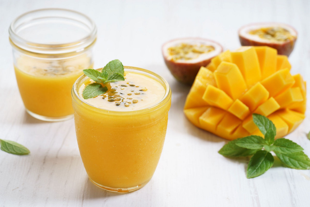 Mango and passion fruit smoothies on wooden background