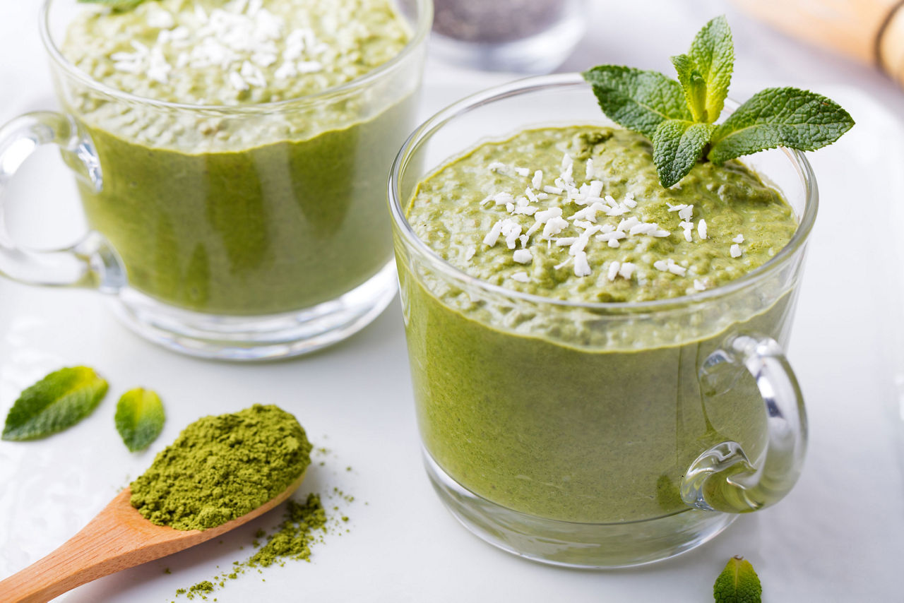 Protein shake with matcha and red beans, Matcha green tea chia seed pudding, dessert with fresh mint and coconut on a white stone background Healthy breakfast