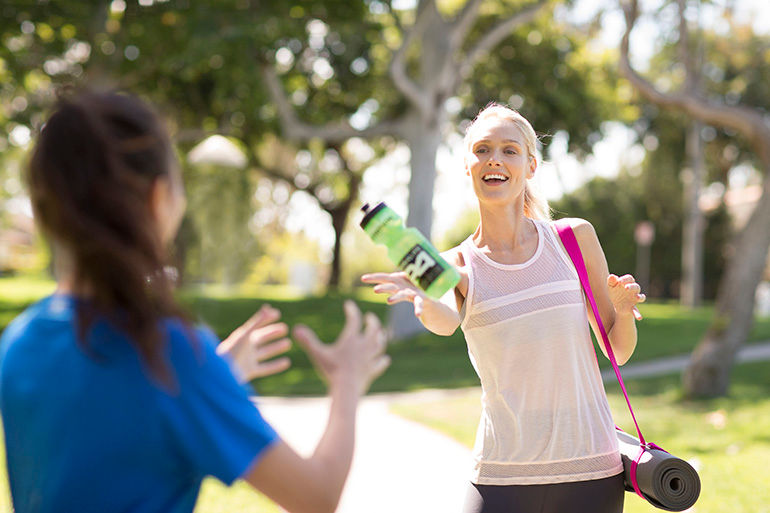 Woman passing a bottle to another woman.