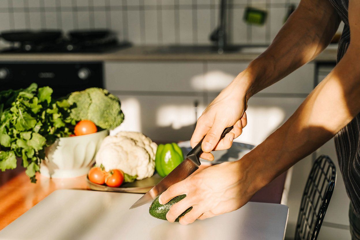 Man cuts avocado in kitchen