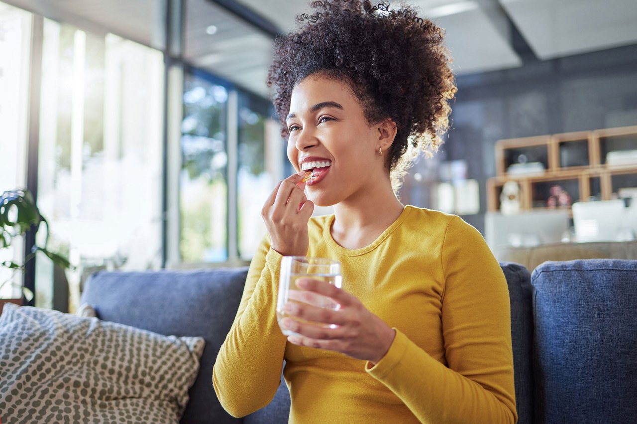 Pregnant woman taking medicine in living room