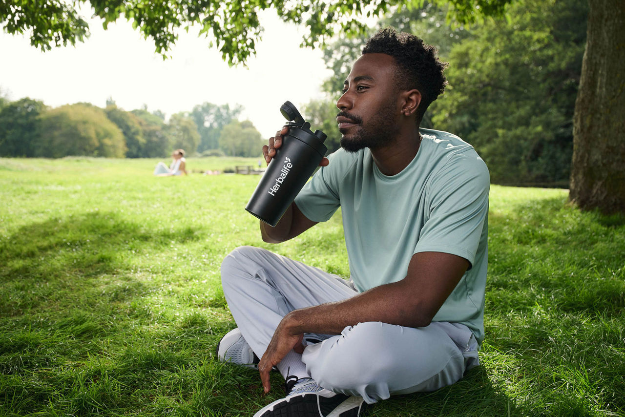 man drinking shake at park