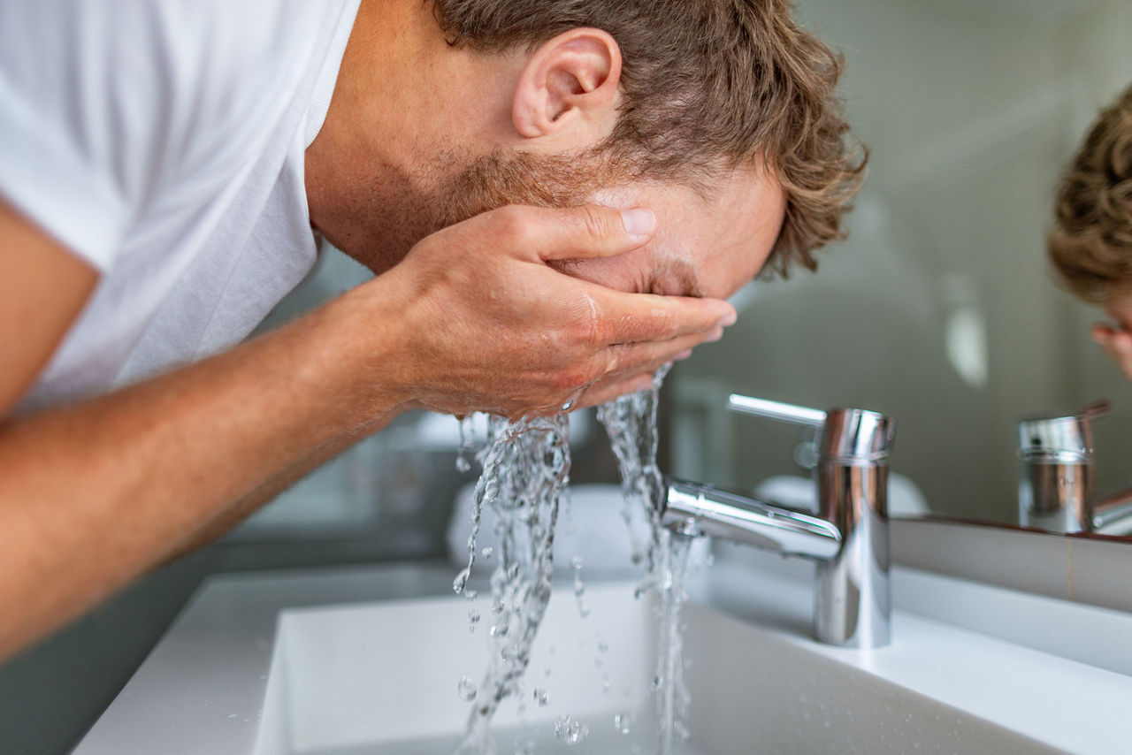 Uomo che si lava il viso al mattino