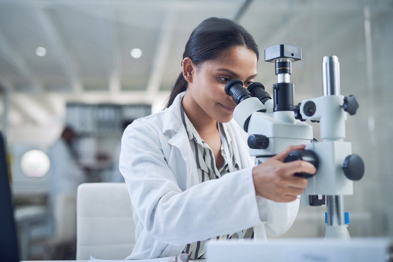 Science, microscope and innovation with a woman in a laboratory for medical research or experiment. Healthcare, medicine and a young indian engineer working in a lab for pharmaceutical development.