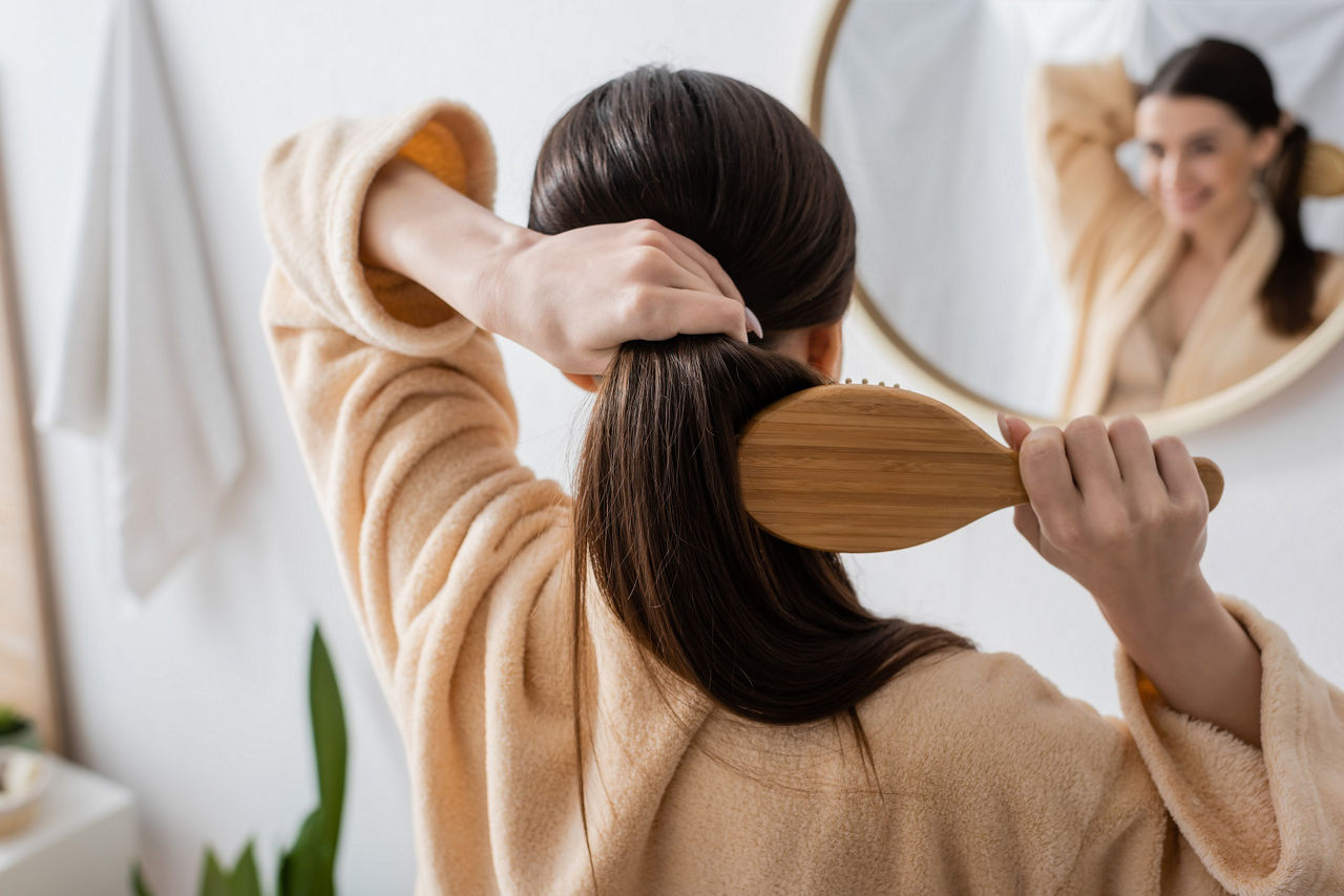 Mulher a escovar o cabelo em frente a um espelho