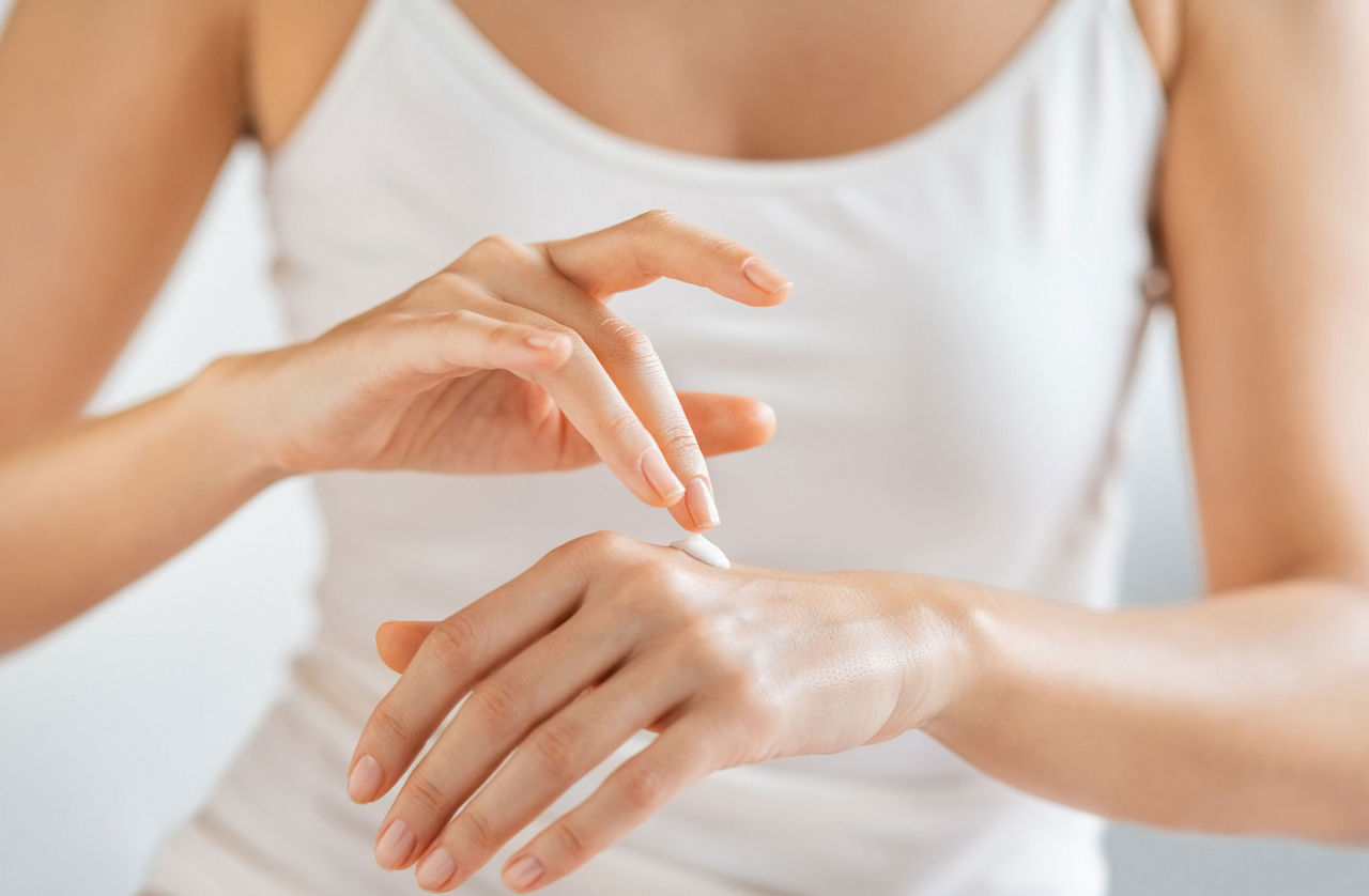 Femme mettant une crème sur ses mains