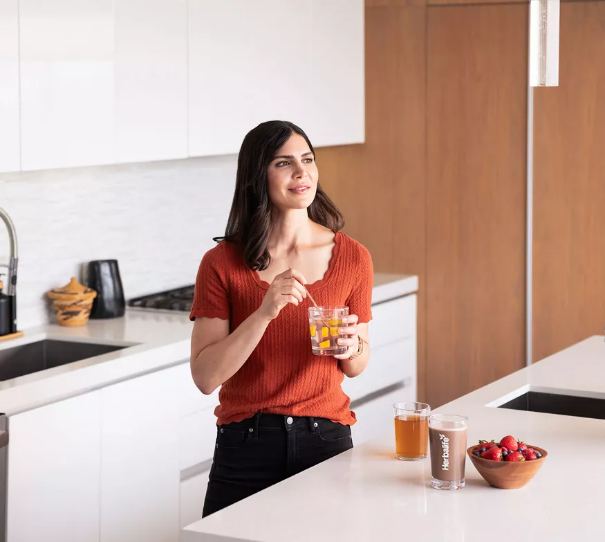 Woman in kitchen with glass of aloe concentrate