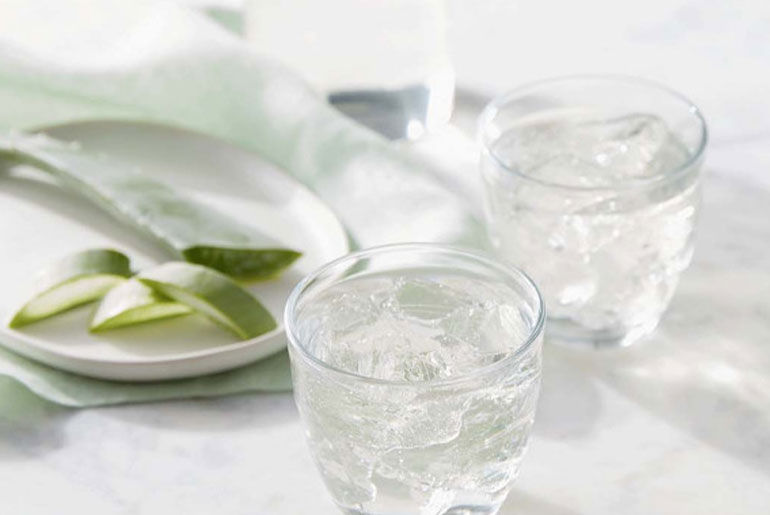 Glasses of water and aloe slices on plate