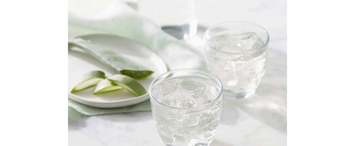 Glasses of water and aloe slices on plate