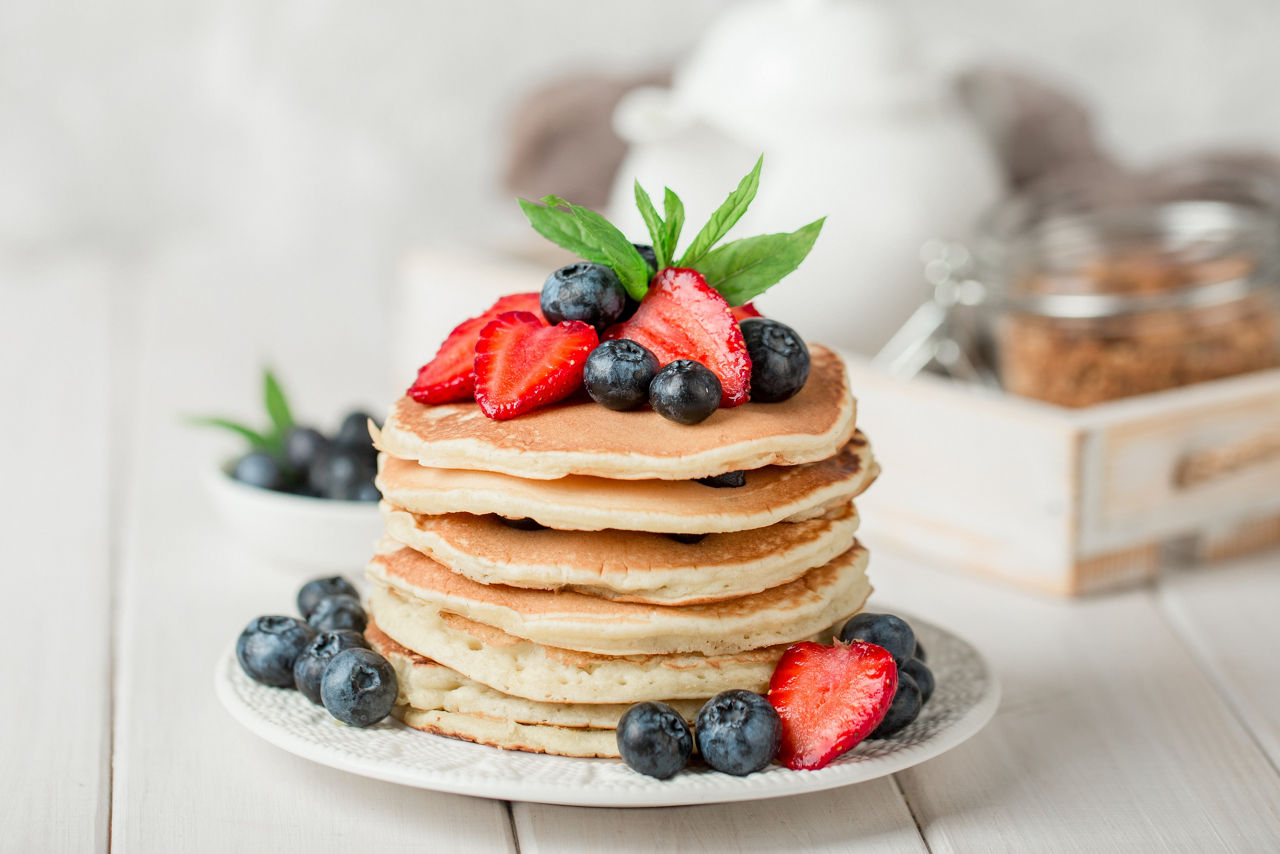 Classic american pancakes with fresh berry on white wood background. Summer homemade breakfast.