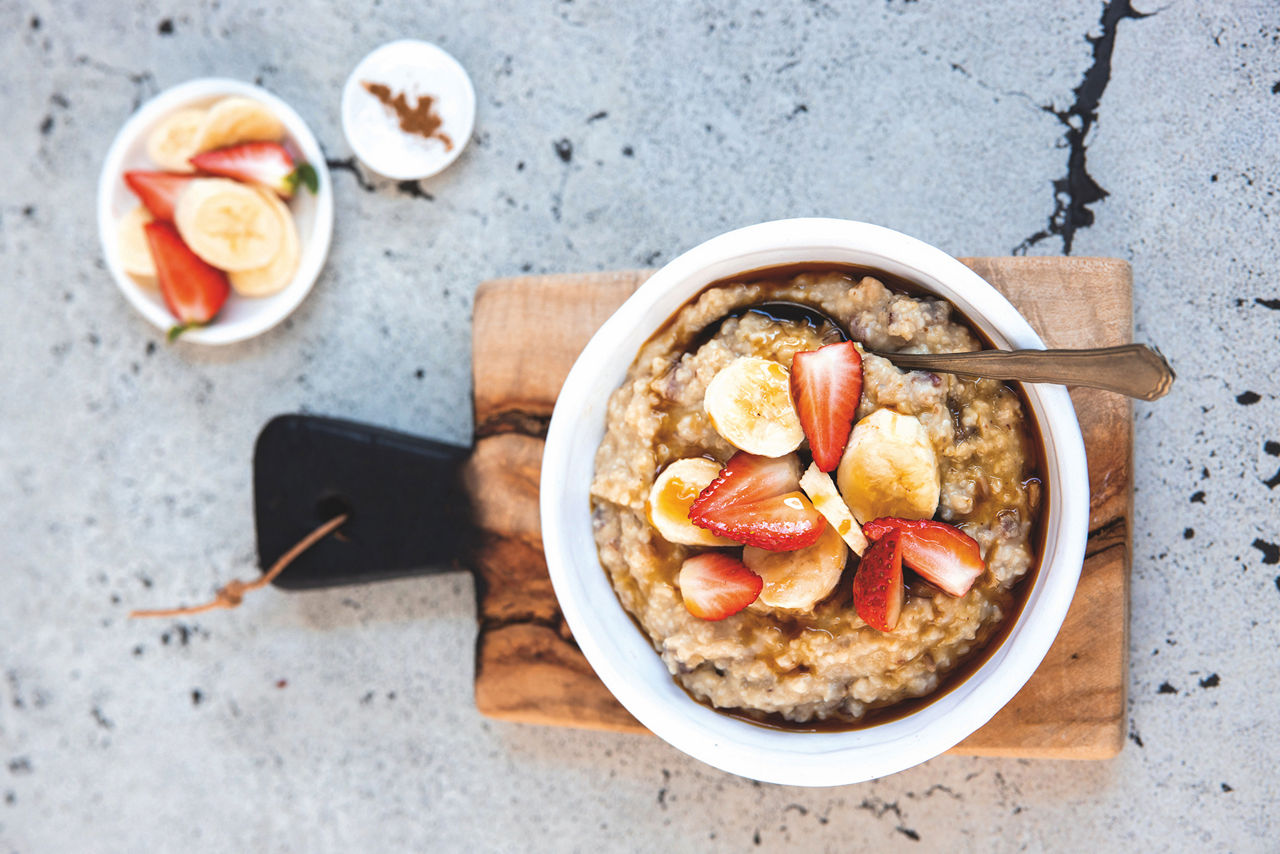 Eine Schüssel Datteln-Zimt-Porridge mit Bananen- und Erdbeerscheiben obendrauf