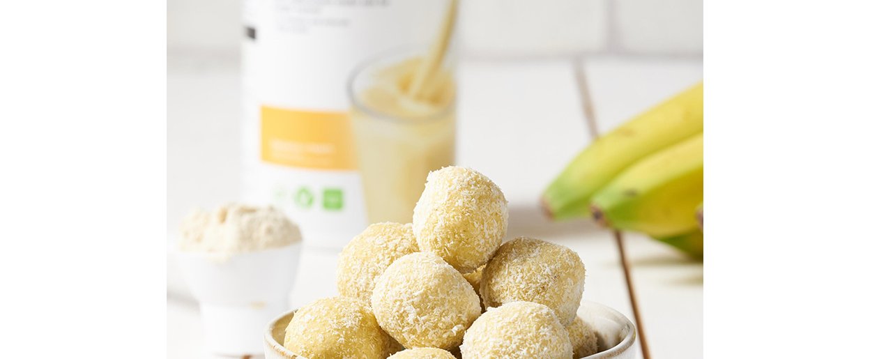 proteinkugel in einer schale mit einer formula 1 banana cream dose und bananen im hintergrund