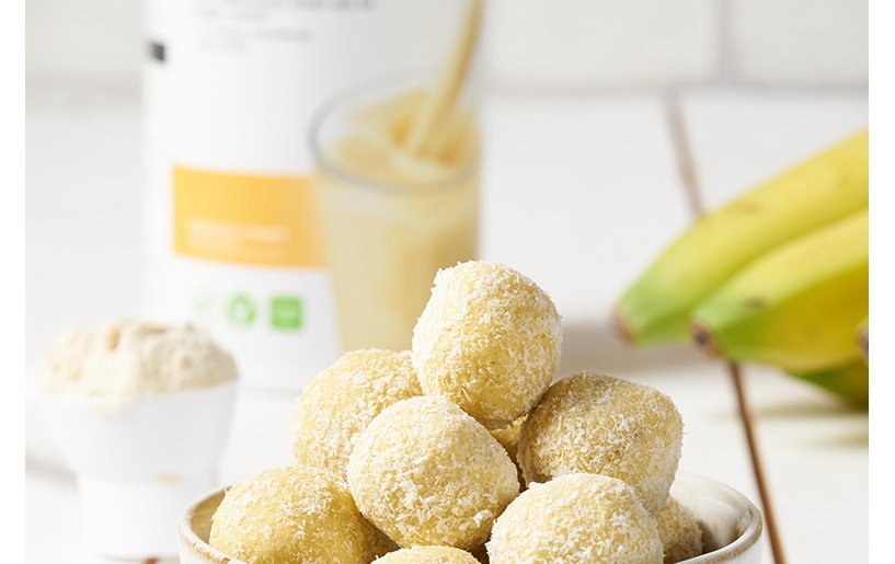 proteinkugel in einer schale mit einer formula 1 banana cream dose und bananen im hintergrund
