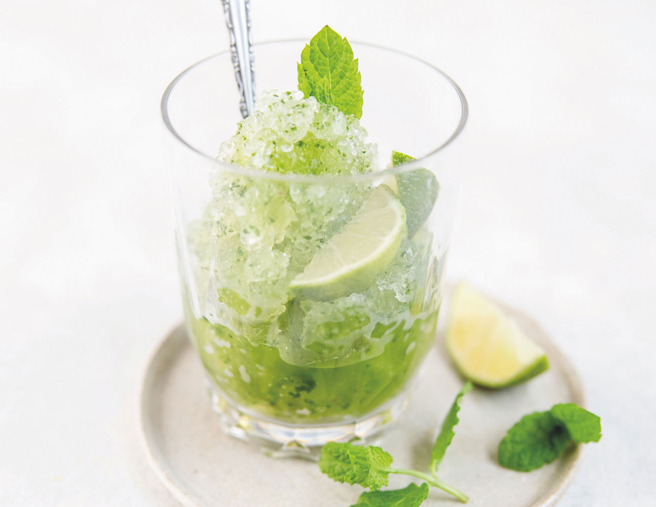 Un vaso de nojito helado con lima y hojas de menta fresca