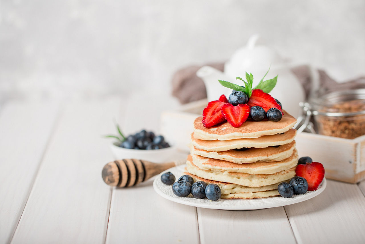 Classic american pancakes with fresh berry on white wood background. Summer homemade breakfast.