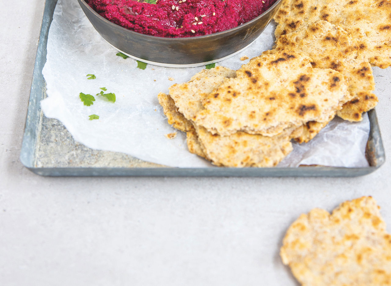 Flatbread on a tray next to beetroot hummus