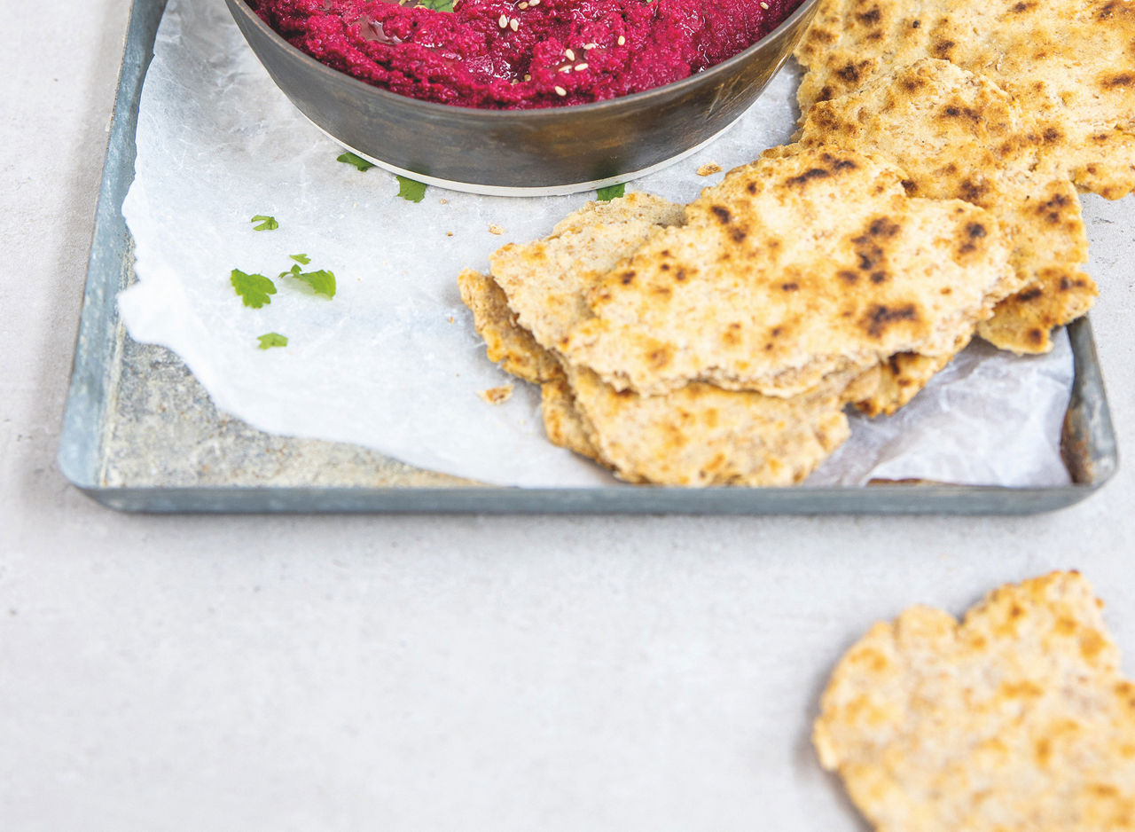 Pane piatto su un vassoio accanto a hummus di barbabietola