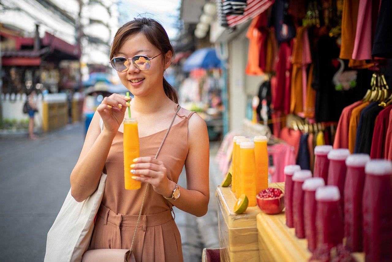 Young girl enjoying juice drink bought from street vendor in Bangkok