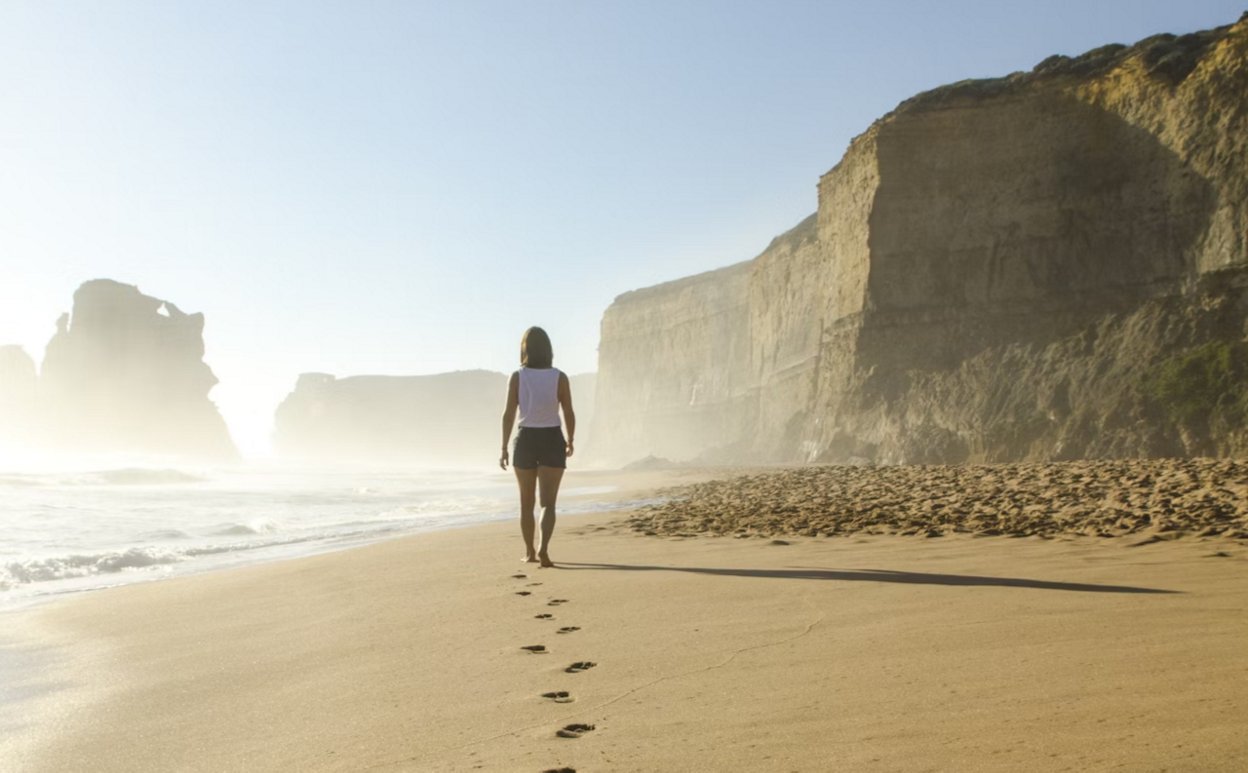 Persona caminando en la playa durante el atardecer